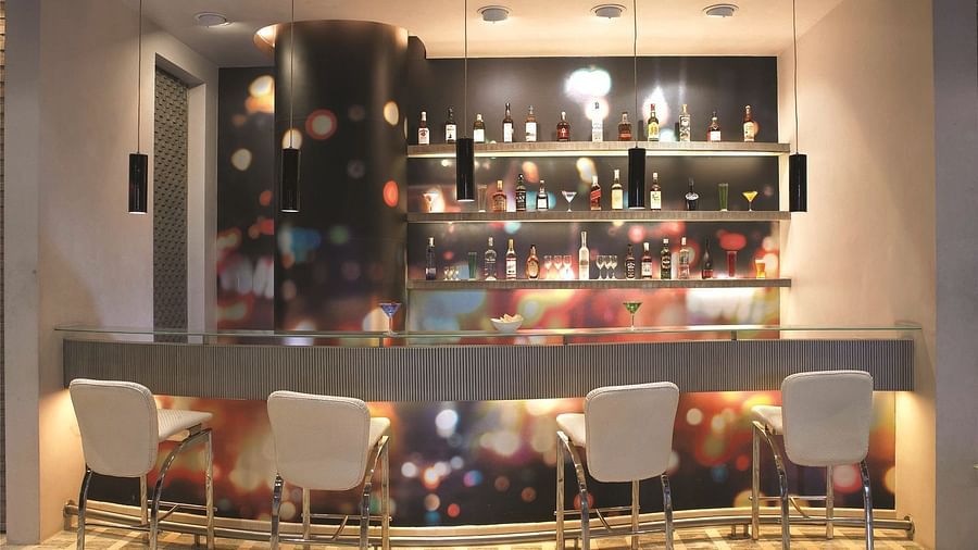 Image of zebra lounge at our hotel featuring a bar stand with chairs and bottles of alcohol | Mirage Hotel