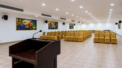 Orchid Hall featuring a podium with microphone and gold chairs at Chariot Beach Resorts, well-suited for presentations and events.