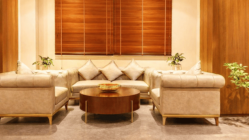 Sitting area of Pride Premier Darjeeling featuring sofa sets and centre table with few plants around.