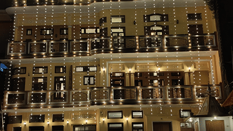 An illuminated facade with mutliple windows and doors. | Hotel Devnadi, Haridwar 
