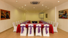 Frangi Pani Hall set up with round tables in red linens and purple sashes at Chariot Beach Resorts, perfect for elegant gatherings.