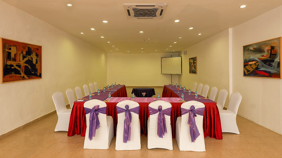 Frangi Pani Hall set up with round tables in red linens and purple sashes at Chariot Beach Resorts, perfect for elegant gatherings.