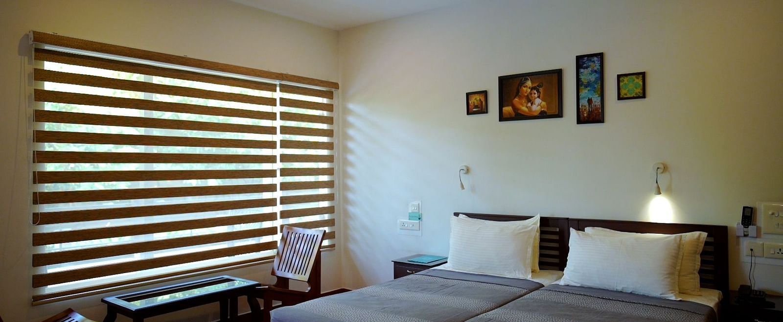 A simply furnished bedroom with a bed, desk, and window blinds.