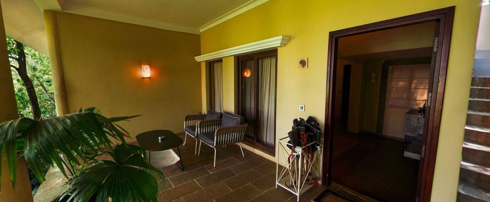 Outdoor area with yellow walls, patio seating, and entrance door beside a staircase at Fireflies Resorts, Kabini.