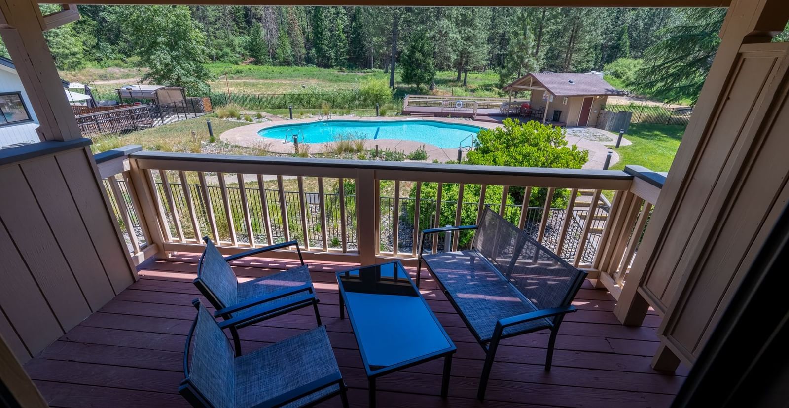 View from the balcony of Deluxe King Room furnished with a seating area, offering a view of the outdoor swimming pool, and landscapes.