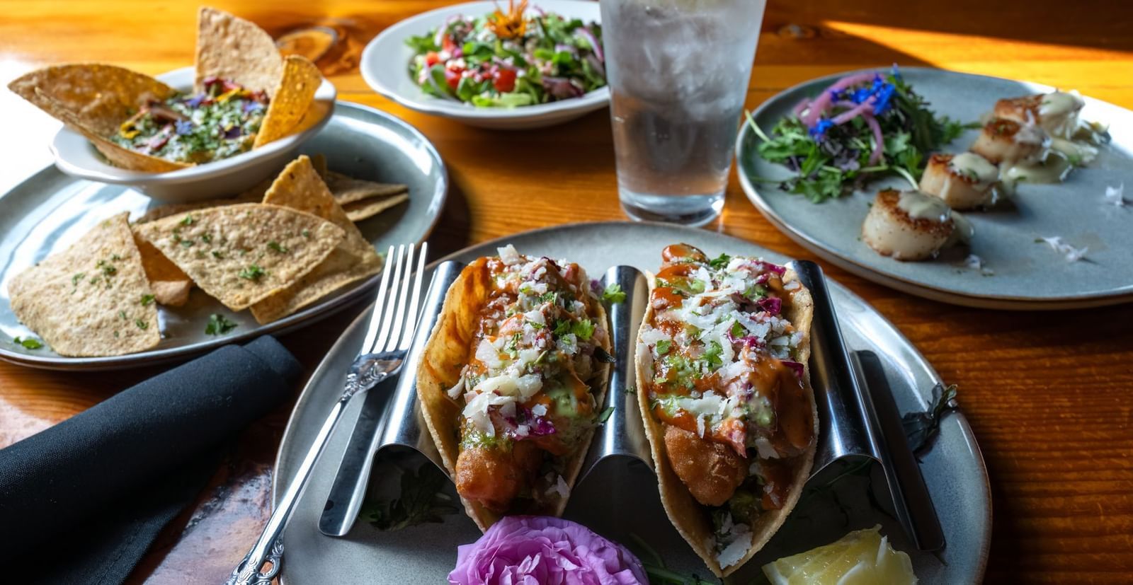 Mexican-inspired dish with tacos, grilled shrimp, pita, and salad served with lemon water at Narrow Gauge Inn.