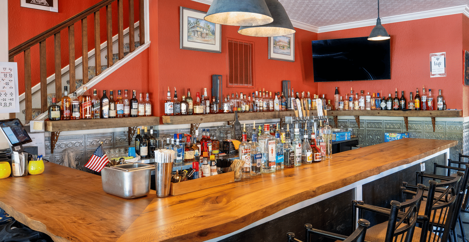 Rustic indoor bar area with high chairs and a wooden counter at The Groveland Hotel.