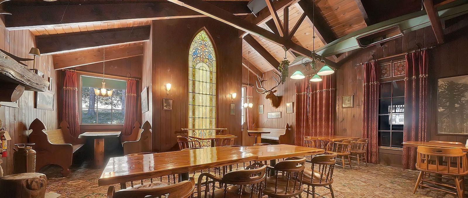 A dining arrangement in the centre of a room with a carpet and large wooden beams - Narrow Gauge Inn - A Serenite Hotel Near Fish Camp.