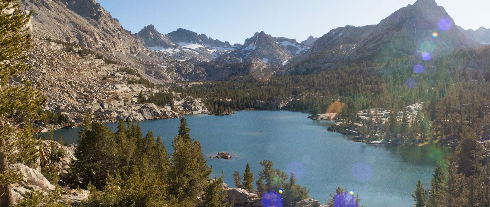 Crystal-clear waters of a high-altitude lake nestled among rocky mountains, near the Tallman Hotel.