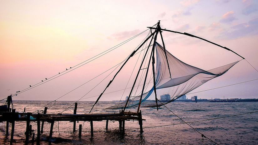 a chinese fishing net by the sea with pink sky in the bakground