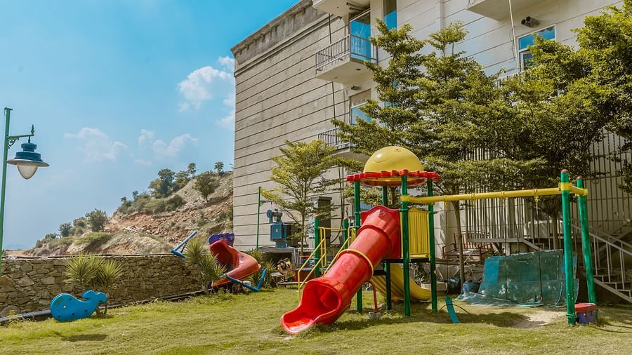 An image of an outdoor park with a lawn and various play equipment
