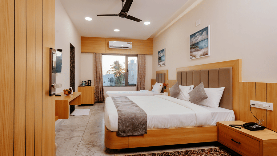 Spacious Pride Room at Daksh The Grand Goverdhan, Dwarka, with multiple beds, modern decor, and a view from the window at the far end.