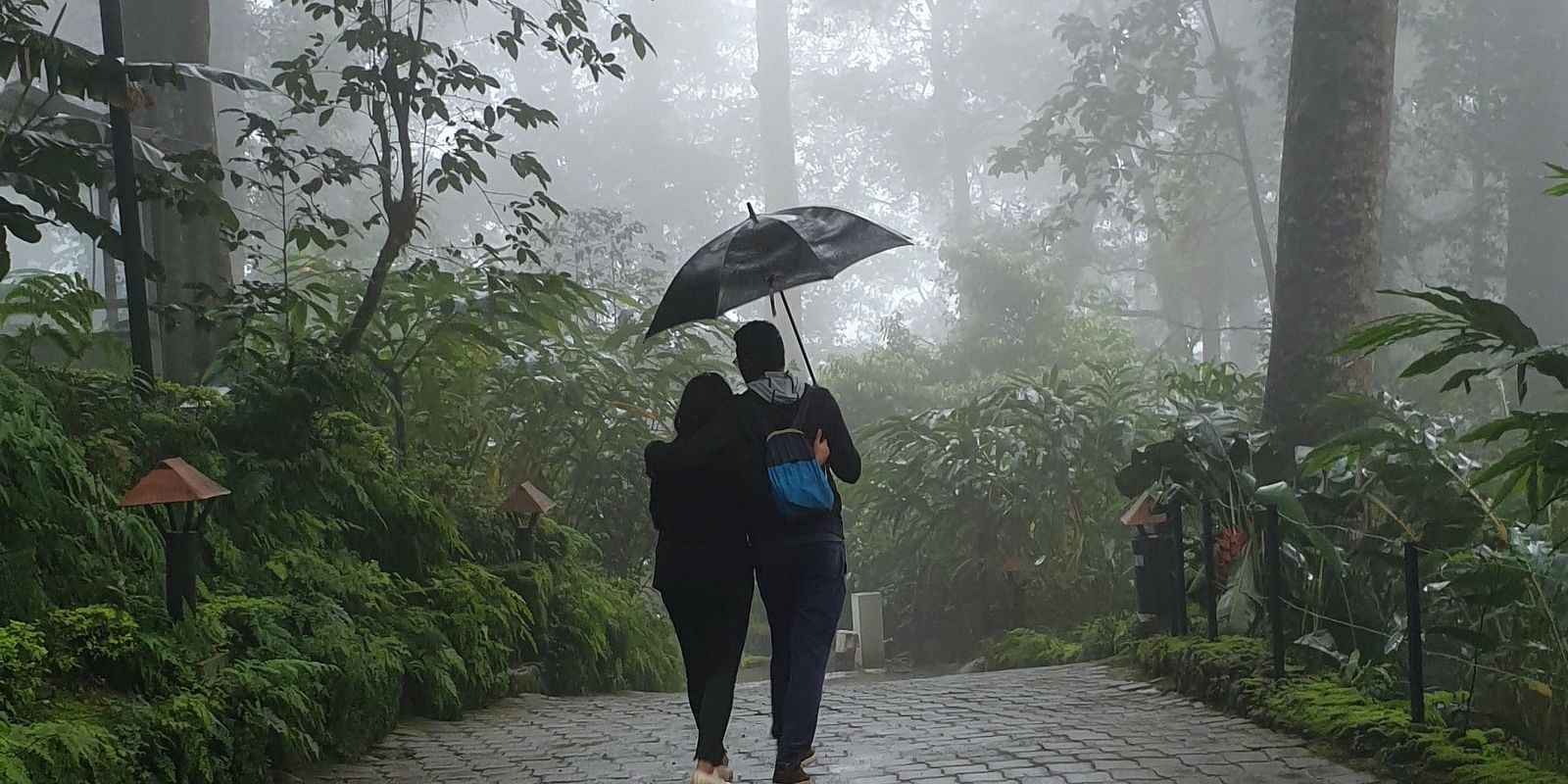 a couple walking in the rain holding an umbrella