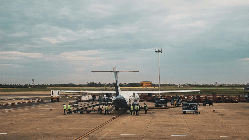An airplane is parked on an airport tarmac under a cloudy sky.