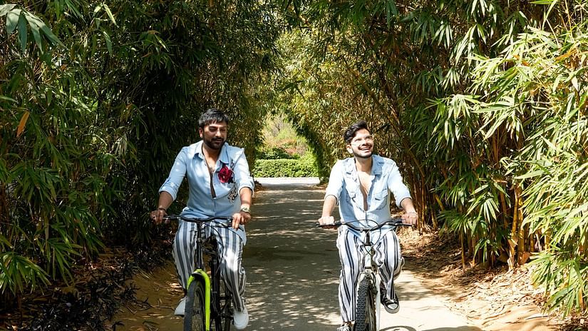 Two men riding bicycles amidst lush greenery - Karma Lakelands.