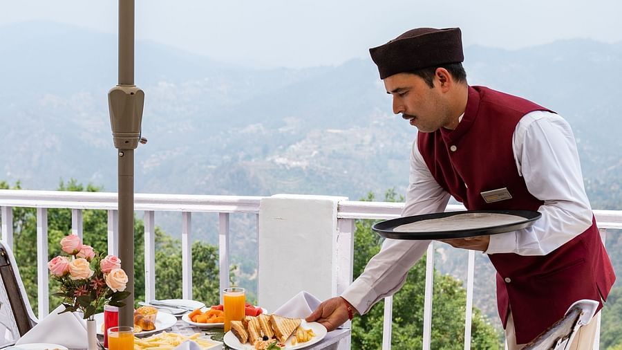 A man serving in sit out dinning area at Te Aroha By Shervani, Mukteshwar