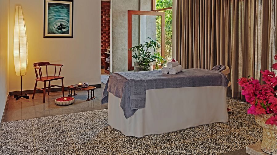 A  therapy room with a bed, curtains, and artwork, indoor setting - Shreyas Retreat