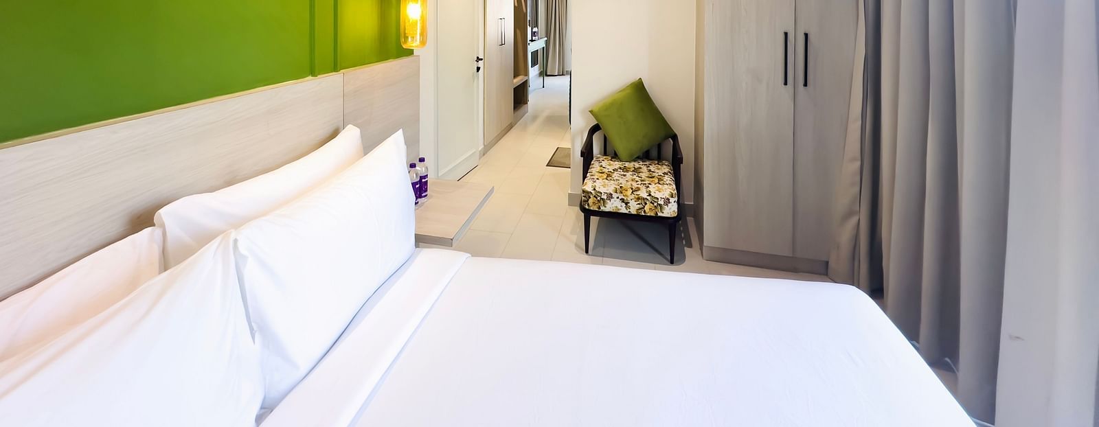 A hotel room with a large bed, a comfortable chair and a cupboard - Wonder Hills