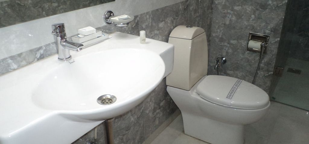 Bright bathroom with a large sink, toilet, and glass partition