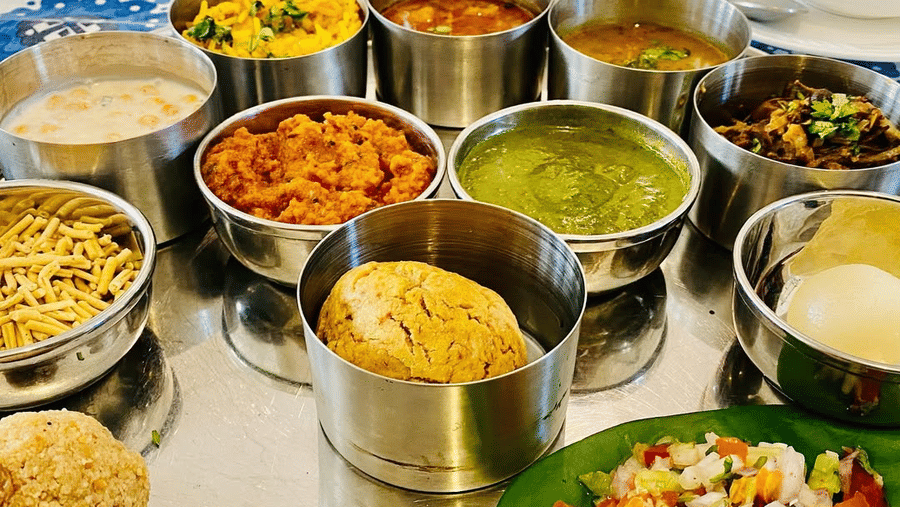 A buffet spread with multiple serving bowls and dishes on a table at Akshay Niwas Boutique Hotel by Amantra, Udaipur, with salads and cooked items visible.