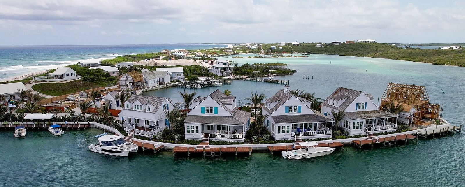 Marina scene with small boats docked near a group of seaside cottages and overwater villas in a protected inlet | Abaco Inn
