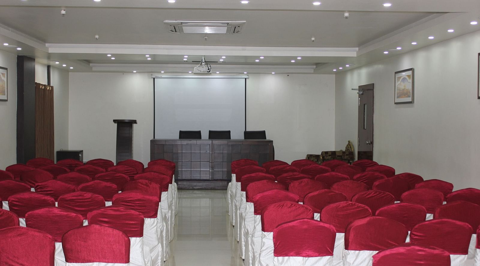 Image of Swathi Hallwith chairs arranged and lights on the ceiling at Hotel Green Apple