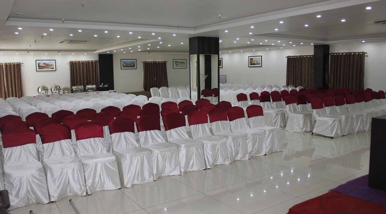 Jyothi hall with seats arranged and lights on the ceiling at Hotel Green Apple