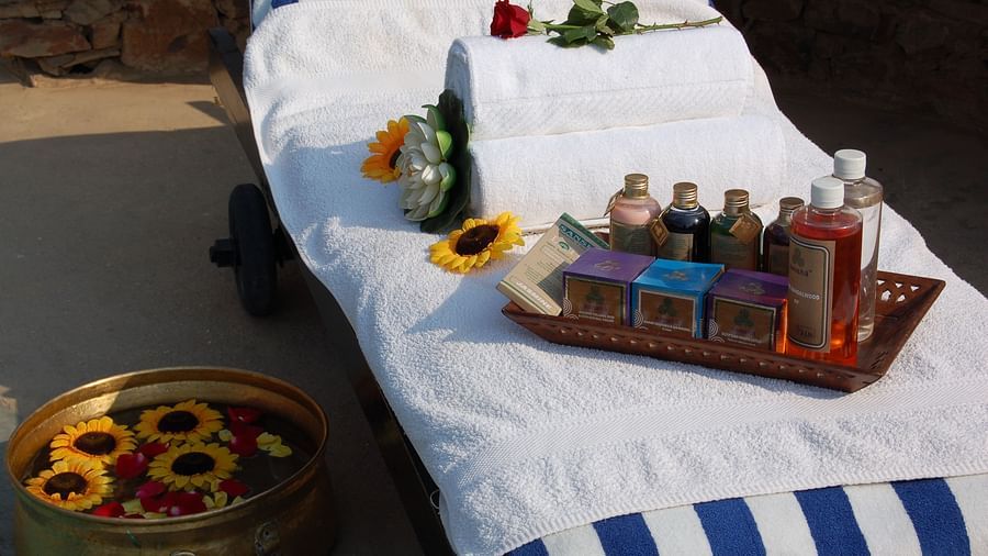 A comfy make-shift bed with a container of water with sunflowers floating on it - Spa hotel  in Alwar