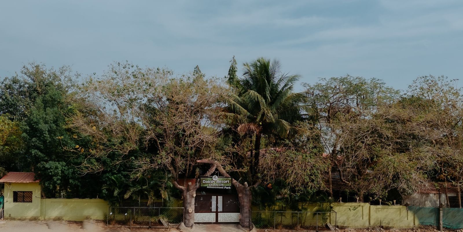 A view of the entrance to Daksh Resort & Amusement Park, Sasan Gir, covered with greenery.