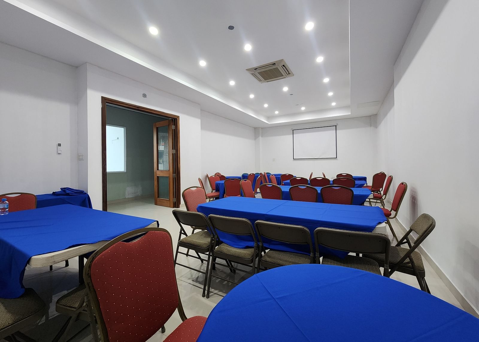 An image of Imagination  Lounge, our event hall in Montego Bay with chairs placed around long tables and a projector - Hotel 39, Jamaica (Montego Bay)