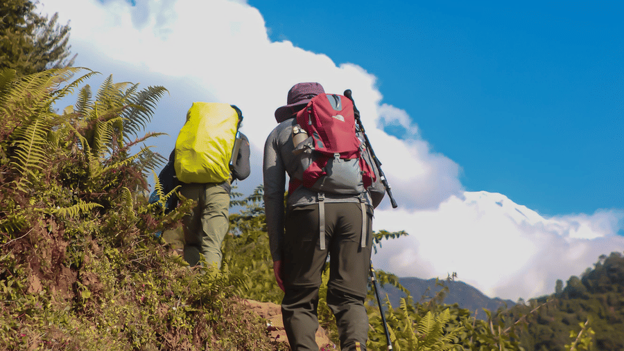 Two people trekking up a dry mountain path.
