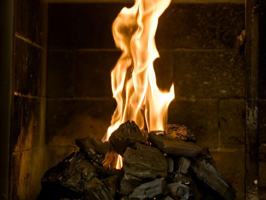 A fireplace with burning charcoal and flames erupting from it.