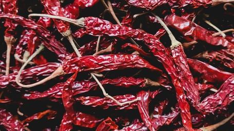 A pile of bright red dried chillies at a market stall, in a close-up overhead shot.