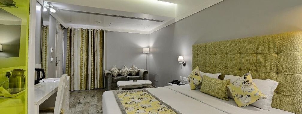 Elegant room with a large bed, table, chairs, and TV unit at Hotel Emerald, Chandigarh