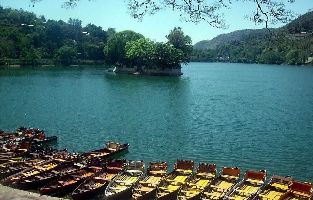 An image of a lake where several boats are anchored and on a distance there is a small island