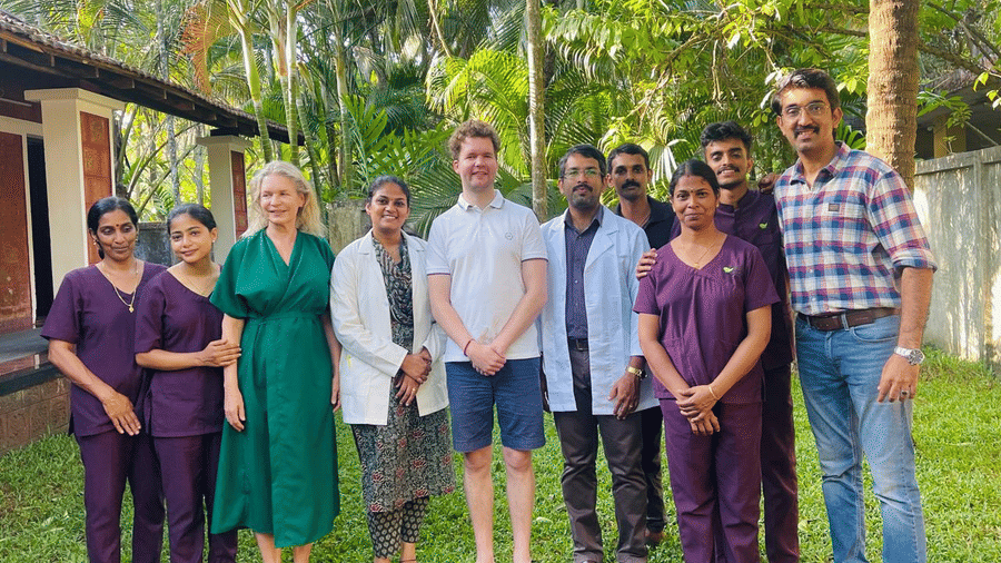 A group of people  along with doctors standing outside in a lawn and posing at Ayur On The Beach Nattika.