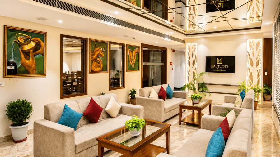 Lobby seating area with sofas, cushions and framed artwork on the walls at Eastlynn Resort, Rishikesh.