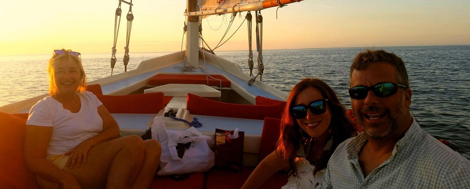 Three people sitting on a sailboat at sunset near Casa Morada, our resort in Islamorada.