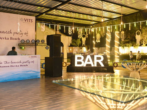 Elegant banquet hall event setup with decorative lighting, bar counter, and floral decor for a wedding celebration | VITS Daman Devka Beach