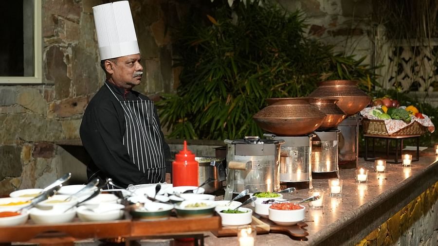 A chef stands behind a candle-lit buffet, ready to serve authentic Indian cuisine - Khas Bagh, Jaipur.