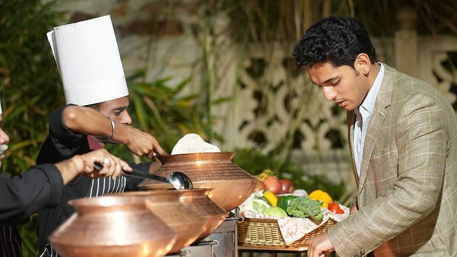 A chef and a guest discuss the menu beside a buffet spread in traditional copper pots - Khas Bagh, Jaipur.