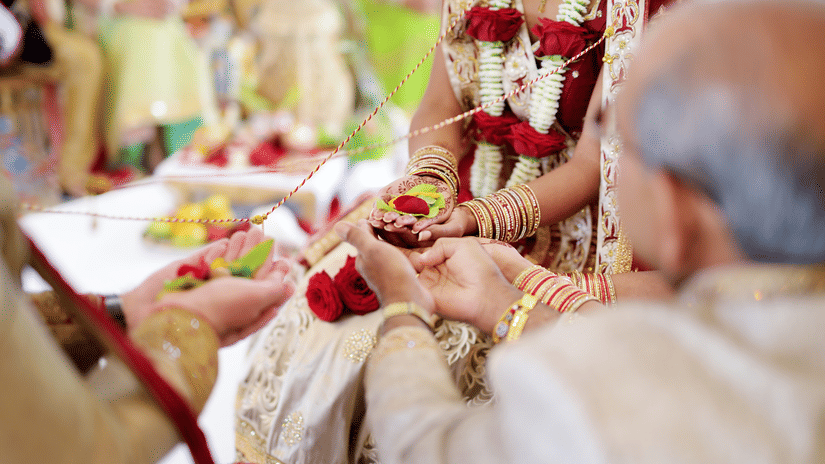 Family members participating in a traditional wedding ritual as the bride and groom exchange ceremonial offerings during the ceremony | Clarks Amer, Jaipur