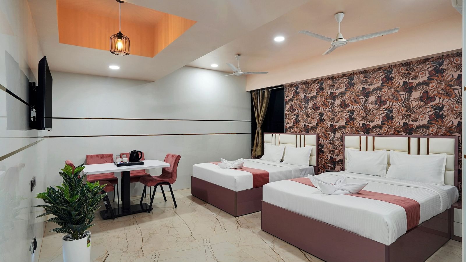 Two seperate king size beds placed in front of television in the Family Room at Hotel Regal Heaven, Pune.