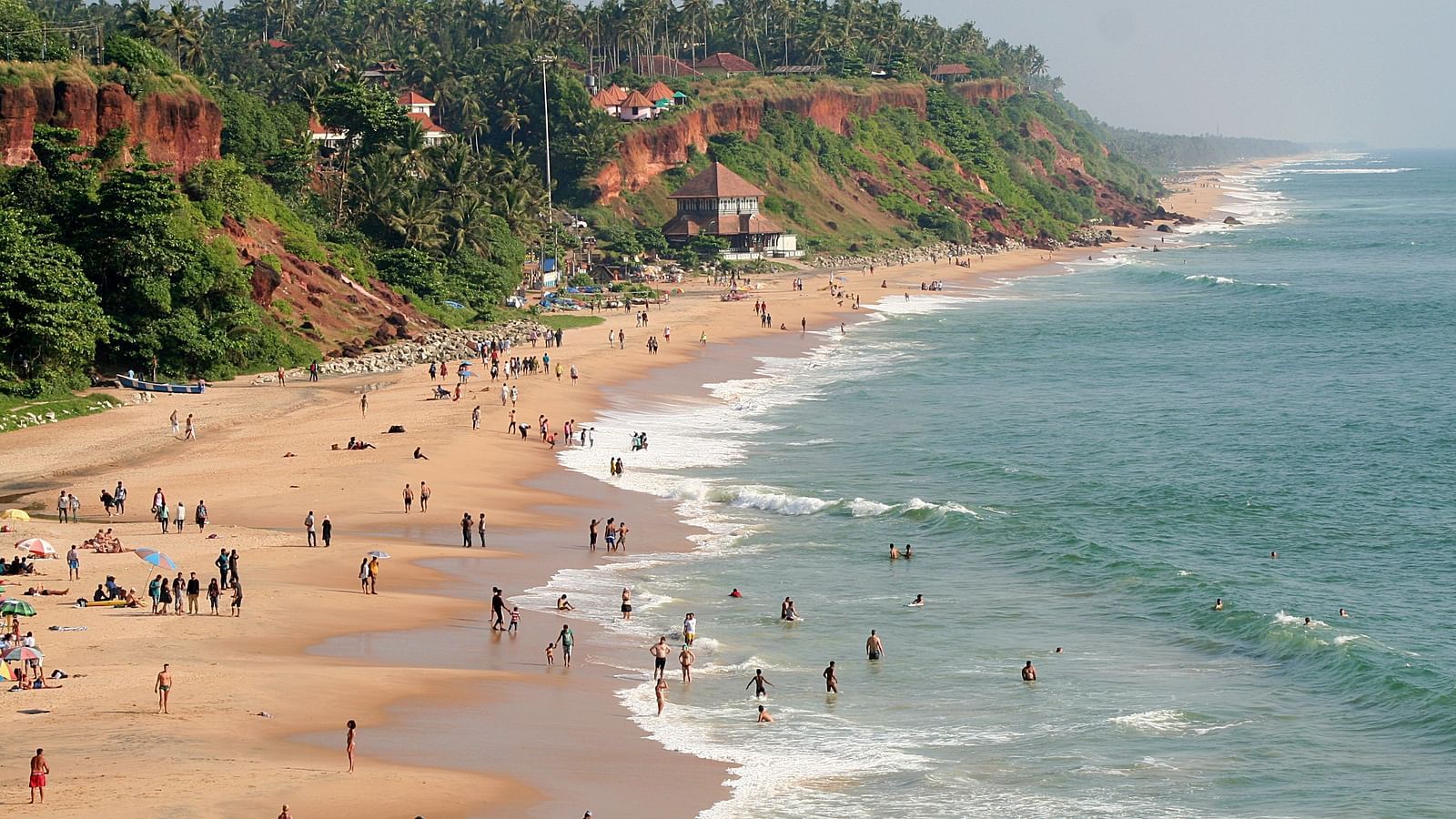 Long view of the beach with people enjoying their time on the shore and hills nearby