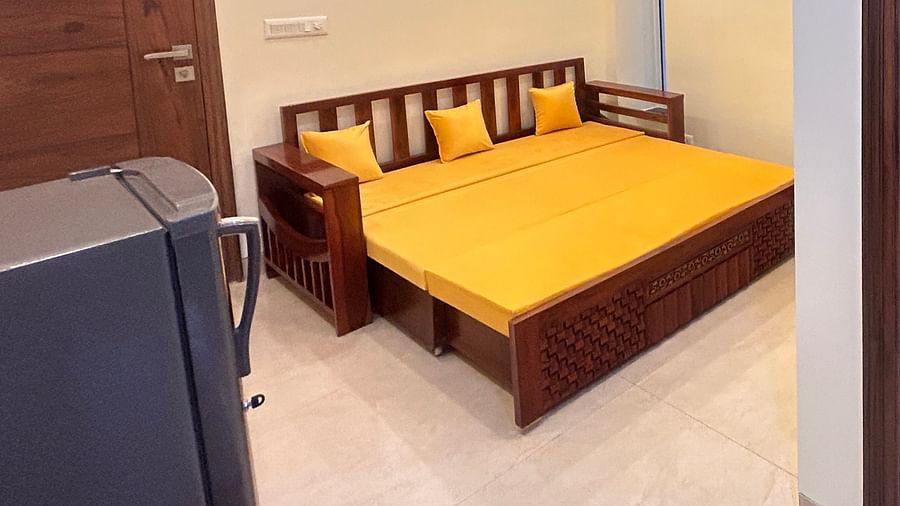 An overview image of both the room where one room consist of sofa cum bed, a fridge, and the other room has a bed with pillows and a bedside table - Lime Tree 1BHK Serviced Apartment near Medanta Hospital