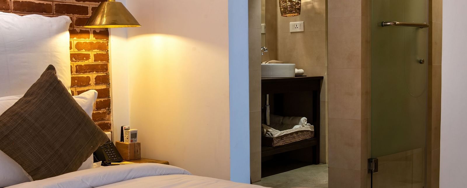Room with twin bed, bed side table, lamp, and the washroom area - The Nanee