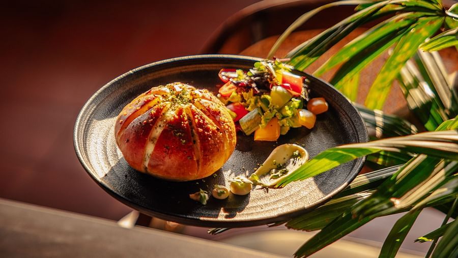 Gourmet dish featuring stuffed bread and a colorful salad on a black plate. | The Icon Select by Bhagini, Mahadevapura
