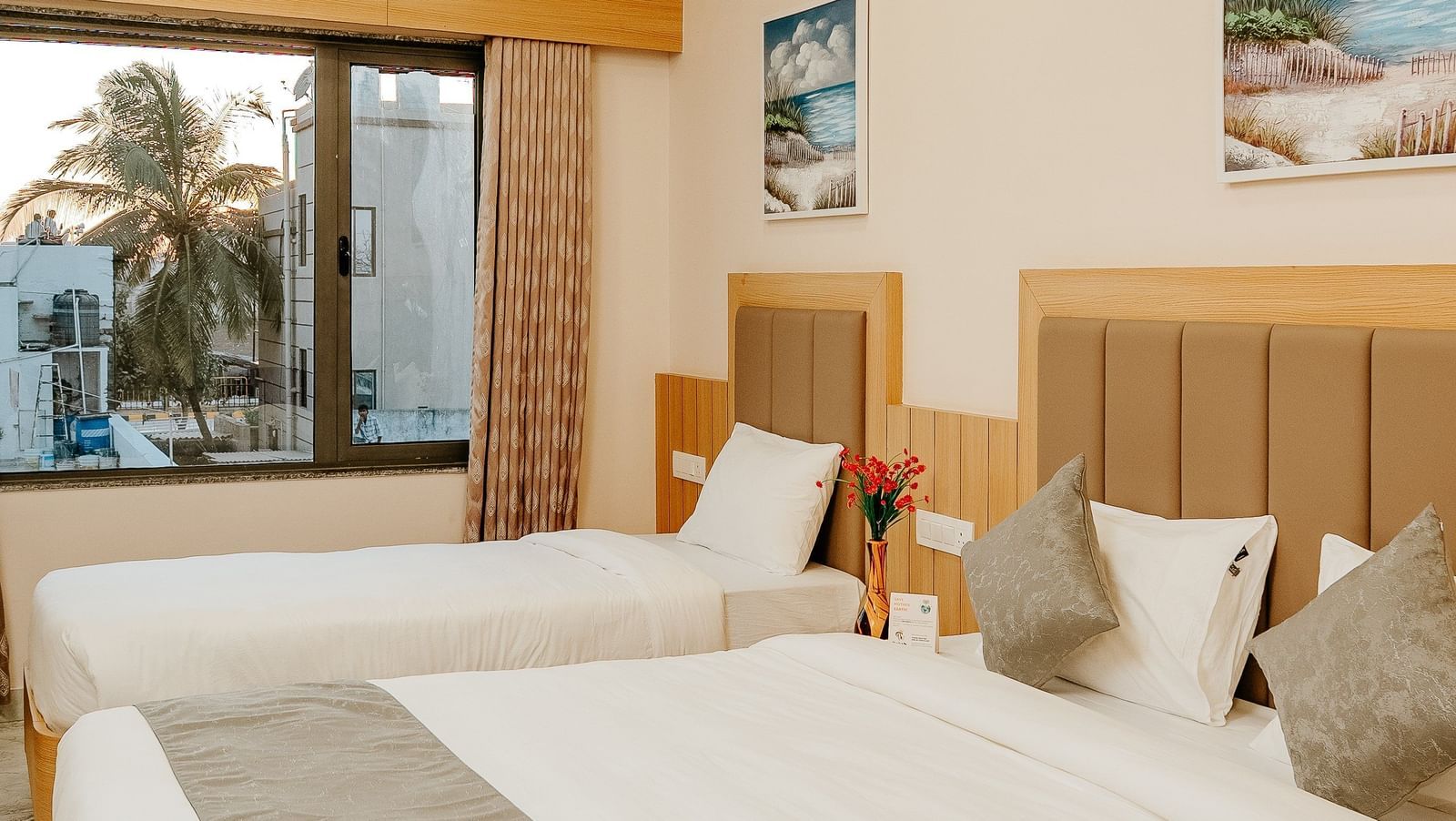 A bright bedroom at Daksh The Grand Gowardhan, Dwarka, featuring a comfortable king size bed and a single bed along with a ceiling fan.