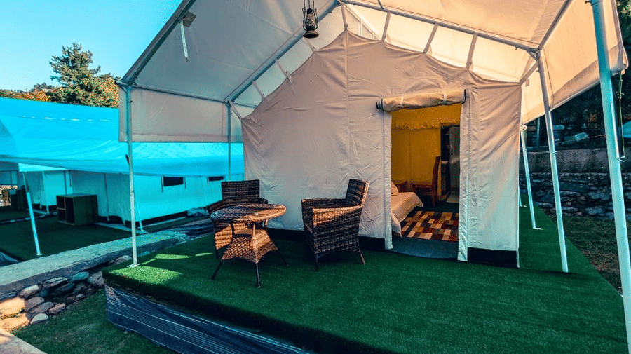 Exterior view of a luxury tent at Dawat e Drung by FrozenFall Resort, Drung, Tangmarg, showing an elevated porch with outdoor seating.