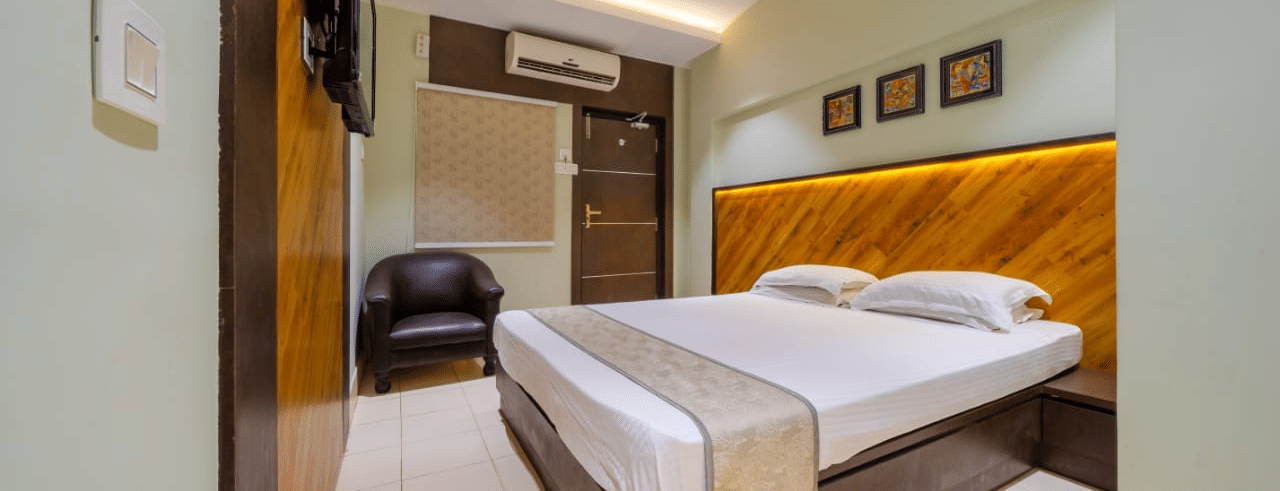 Spacious bedroom with a double bed, wall arts, an A/C, a seating area, and modern lighting – Hotel Dolphin Puri
